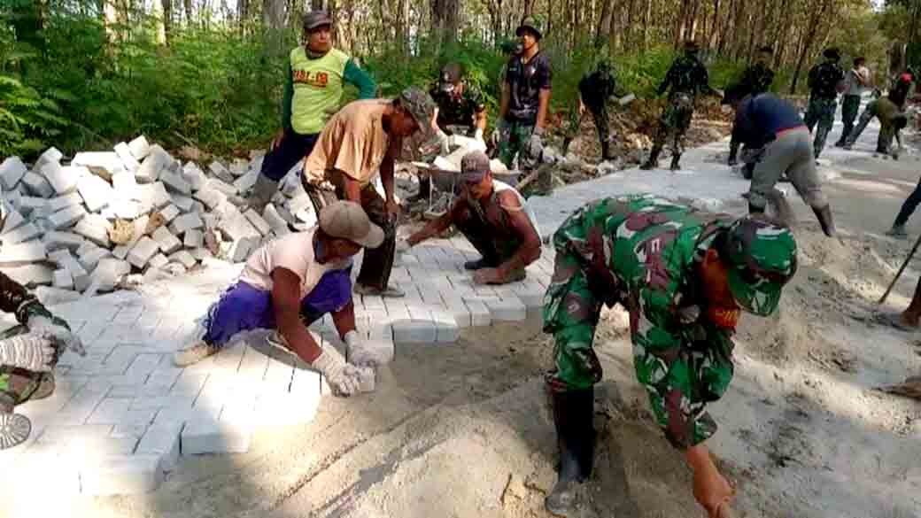 Warga Dan Satgas Tmmd 121 Kompak Angkat Paving Dan Bersinergi Dalam Pembangunan Jalan