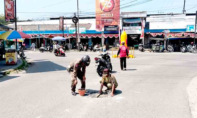 Satpol pp kedungpring tutup lubang jalan di depan pasar, warga diminta waspada 2
